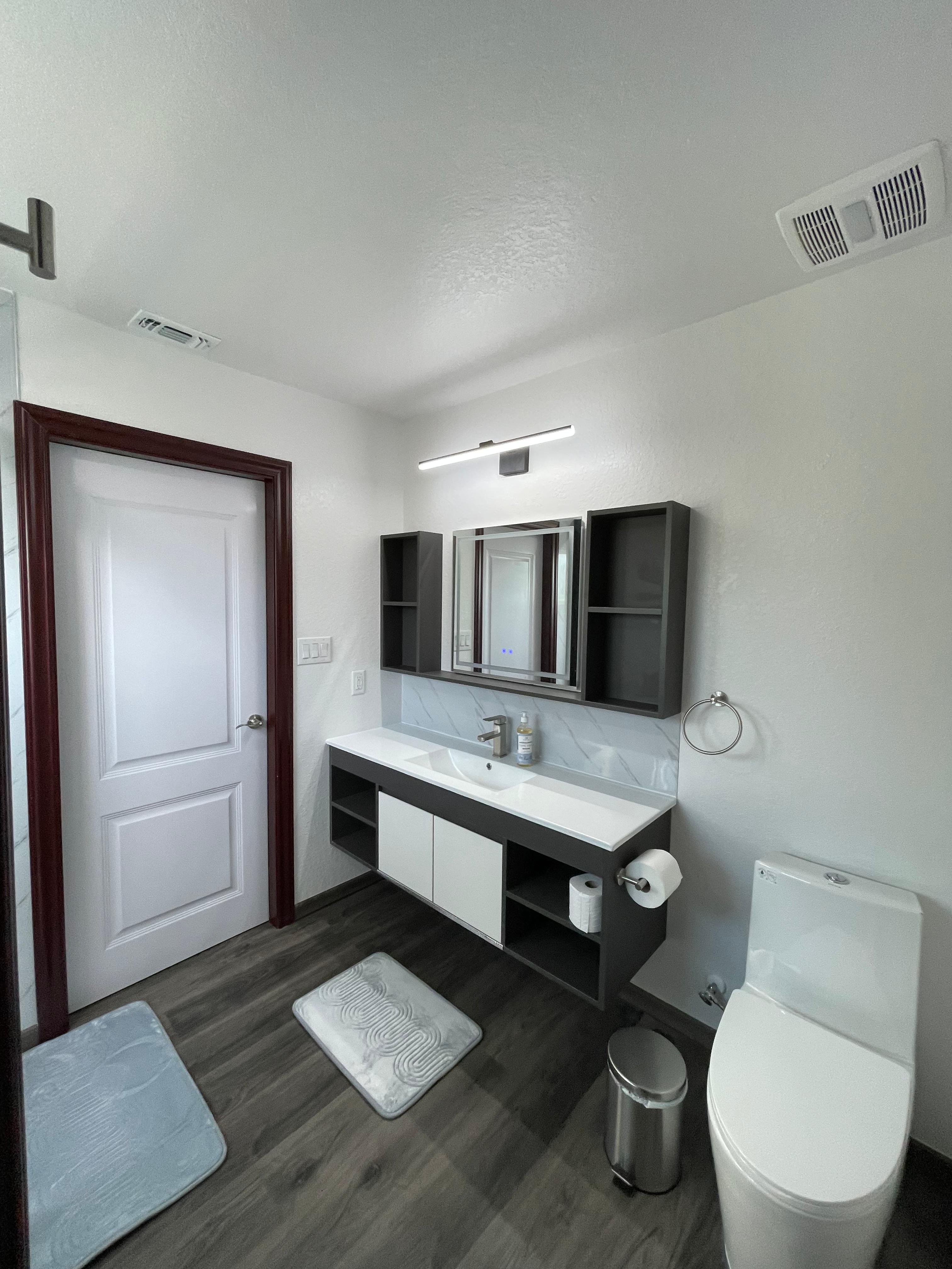 Townhome bathroom with double vanity, toilet, mirrors, and white shower door