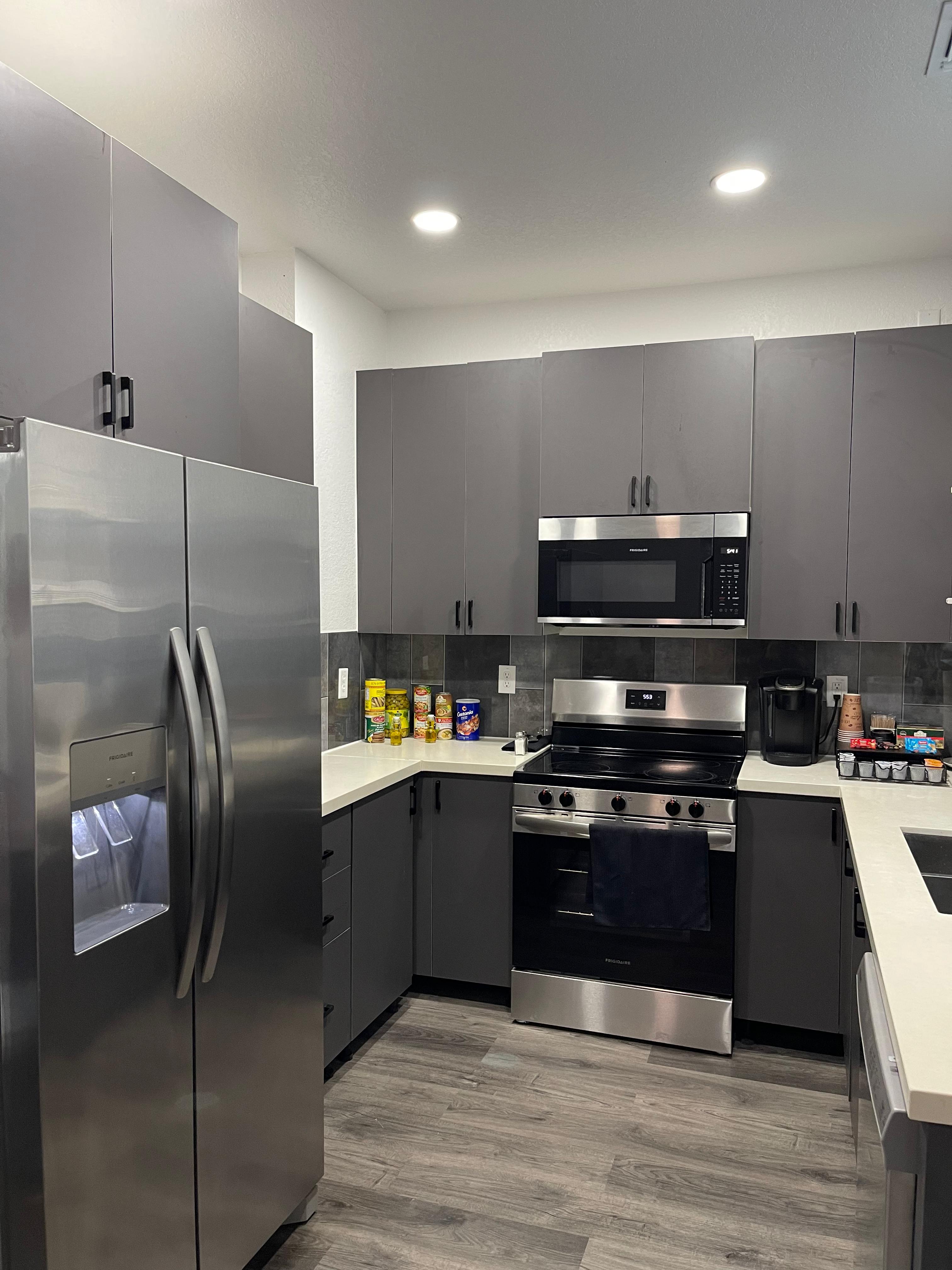 Compact townhome kitchen angle with refrigerator, range, microwave, and gray cabinets